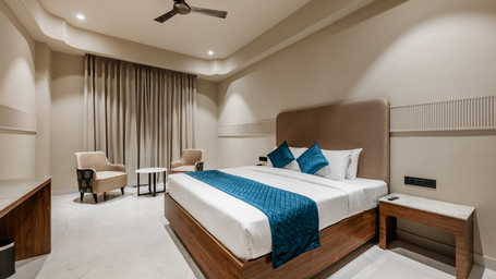 A king size bed, a pair of armchairs, and a bedside table at Hotel Highway King, Harmada.