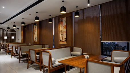 A restaurant featuring wooden tables, padded seating, dark blinds, and pendant lights at Hotel Sonar Bangla, Ajodhya Hills.