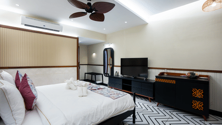 A stylish suite in Susunia with a king size bed, patterned flooring, ceiling fans, and a television unit placed beside the seating area | Hotel Sonar Bangla