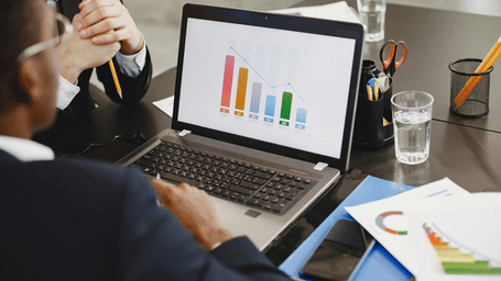 Professionals using a laptop showing growth charts in the hotel business centre.