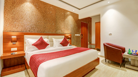 Side-angle shot of a bright hotel suite with red accents and warm wood finishes - Hotel Velocity