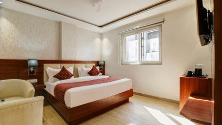 Wide-angle view of a well-lit hotel bedroom with a ceiling fan and minimalist decor - Hotel Velocity