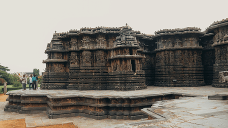 A view of Halebidu temple, a UNESCO World Heritage Site which has intricate and complex design. with a blue sky in the background.