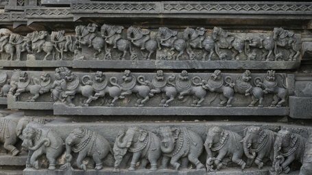 Ornamental stone frieze displaying a sequence of carved animals in motion.