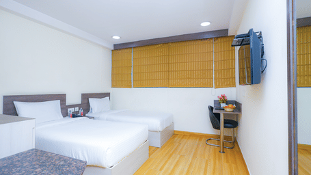 A light filled hotel room featuring a comfortable bed, a small desk, and a television - Hyphen Business Hotel, Noida