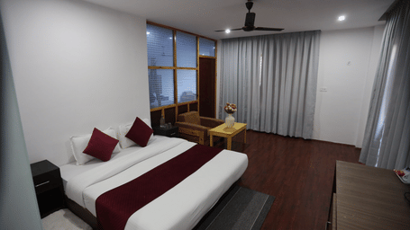 A room with a large bed, pillows, spreads, windows, and soccers. | Indus Serinity, Leh Ladakh