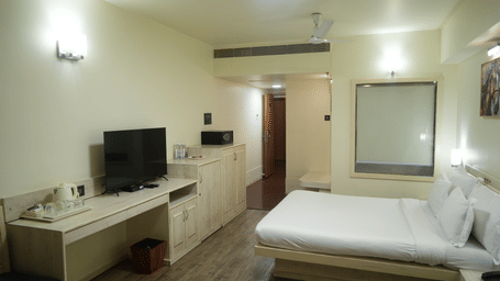 A bed facing a television desk unit at Infiniti Hotel, Indore.