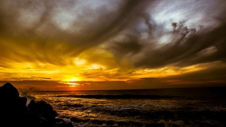 Dramatic sunset over the rocky coastline with vibrant orange and yellow hues