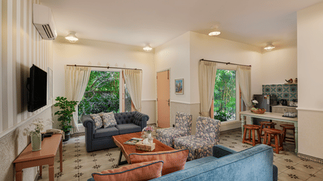 A living room at Karma Chalets with sofas, a TV, a window, and a hallway visible in the background.