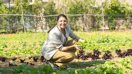 a woman holding a bunch of lettuce on a field - Karma Lakelands.