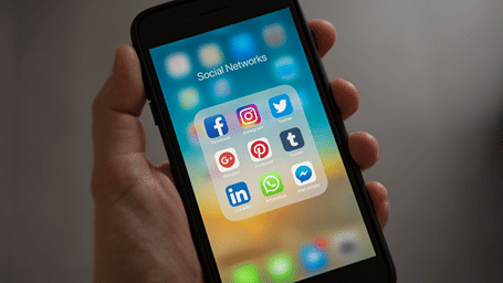 A close up shot of a person holding a phone showing social media apps.