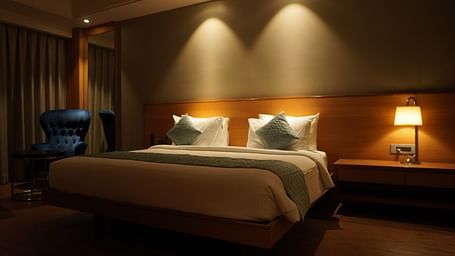 King-sized bed and a bed lamp beside at Grand Suite Kiranshree