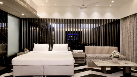 Suite at Kumar Resort by Turtle with a king bed, black slatted accent wall, fluted bench seat, marble coffee table and chevron floor.