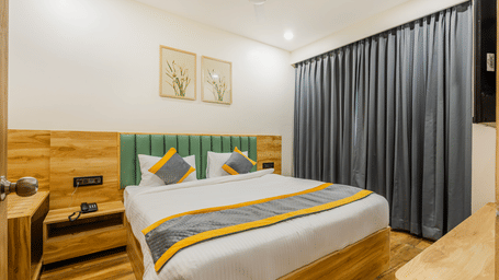A bedroom at Lemonridge by Monday Hotels - KPHB featuring a large bed, green headboard, floral pictures, study desk, and cabinet.