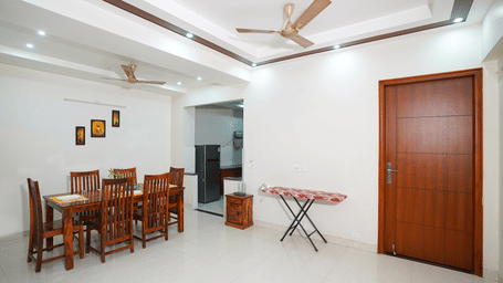 Dining area of Lime Tree Hotels & Service Apartment Private Limited featuring a wooden dining table, chairs, and an ironing board.