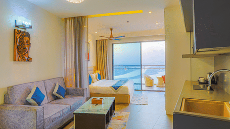 Stylish living area with sofa set, coffee table, and balcony opening to city views at Livbox Supernova, Noida.