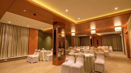 A softly lit function room at Lords Eco Inn Apple Gate is arranged with round tables and covered chairs, ready for an event.