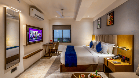 Modern interior with plush bedding, wall-mounted TV, and cozy ambience at Lords Studio Inn, Jamnagar.