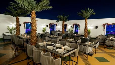 Corner view shot of the Sky Roof featuring well arranged dining tables along side several trees at M2 Square by Monday Premium.