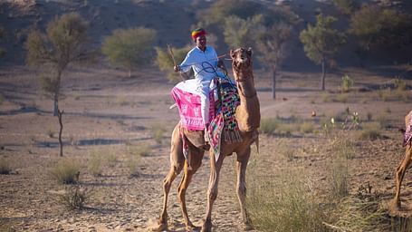 A caretaker riding his camel through the desert - MANVAR Resort & Desert Camp.