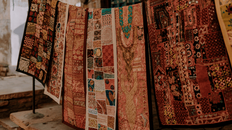 Colorful embroidered textiles displayed outdoors, showcasing traditional Indian craftsmanship.