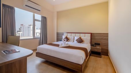 Spacious room at Monday Hotels Amalapuram Heights with double bed, bed-side table, and air-conditioning.