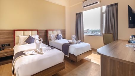Spacious room at Monday Hotels Amalapuram Heights with warm tones, twin bed, air-conditioning, and window view.