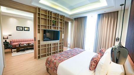 An image showcasing a bedroom of a suite in Kangra in the foreground, with the living area visible in the background - NAMAMI BY ZENQ BANKHANDI