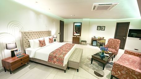 A large suite in Bankhandi featuring a queen size bed with a bed bench, a night stand with a lamp, and cosy furniture - NAMAMI BY ZENQ BANKHANDI