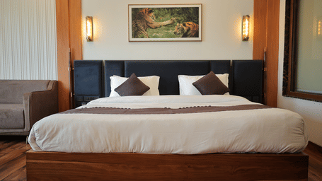 Elegant presidential suite bedroom with a king size bed, wooden flooring, warm lighting, and stylish wall decor.