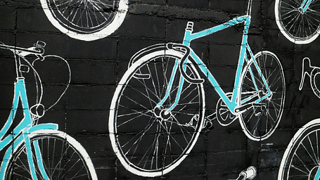 A close up shot of a Graffiti in Bangkok showing bicycles in neon blue and white colours.