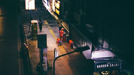 A street photography of a woman working alone in a shop in Bangkok in the night.