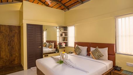 Cosy bedroom with elegant decor and wooden furnishings – Nirantara Resort & Spa