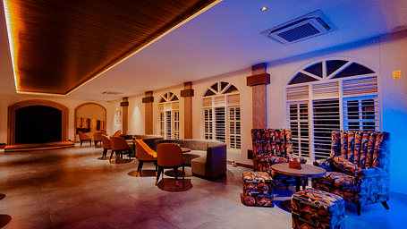 A spacious lounge area at Nirantara Resort & Spa with comfortable seating, decorative lighting, and a view of the outdoors.