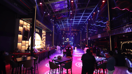 An illuminated space at Nysa Skybar, Bengaluru, with dining area near the bar in a disco light set up.