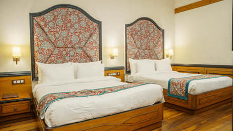 A Family Room at Orsino Spa Resort, Darjeeling, with 2 beds, each with a distinctive patterned headboard and a colourful throw.