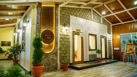 A well-lit interior space of Orsino Spa Resort with wooden ceilings and walls, featuring decorative wall art and potted plants.