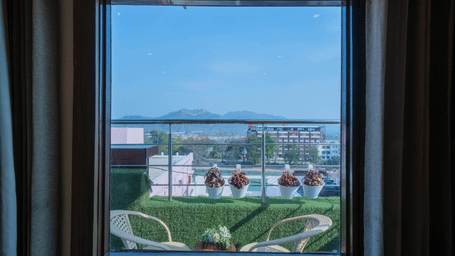 View from a hotel window overlooking a green outdoor terrace area and distant landscape - Perfectstayz Premium at Har Ki Pauri Road (Ganga Heights)