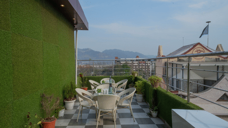 Rooftop terrace seating area with tables and chairs and a view of the surrounding hills - Perfectstayz Premium at Har Ki Pauri Road (Ganga Heights)
