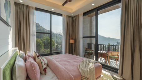 Jacuzzi Suite bedroom view at Perfectstayz Premium Kapilaz, Bhimtal showing a bed near large glass windows and an outdoor balcony.