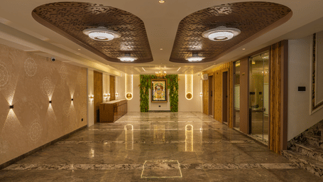 Corridor with marble flooring and wall sconces at Perfectstayz Premium Vrindavan.