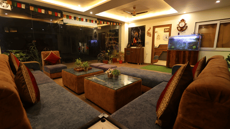 A lounge area with a U-shaped sofa, 2 coffee tables, a fish tank, a cabinet, and flags, at Perfectstayz Value Forest Valley.