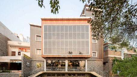 Front view of the Perfectstayz Value Om Palace, Vrindavan building, showing the glass windows and stone-textured ground floor.