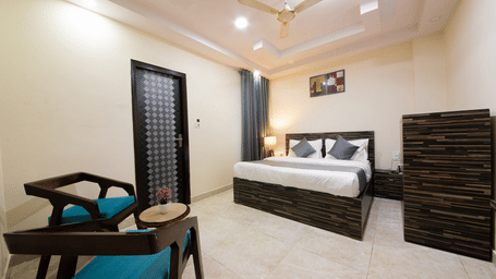 Bright hotel room with double bed, stylish furniture, and seating area - Perfectstayz Value Umra Grace, Haridwar