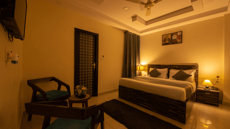 Spacious hotel room with ambient lighting and seating area - Perfectstayz Value Umra Grace, Haridwar