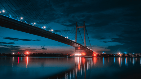 Howrah Bridge over a waterbody with light in the background - Polo Floatel Kolkata