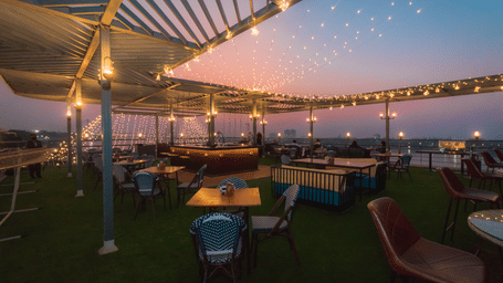 Seating arrangements on a deck with lights on and the evening sky in the background - Polo Floatel, Kolkata