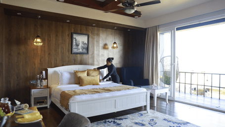 a person making the bed in the Rain Forest Suite - Polo Cherrapunjee Resort