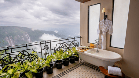 An image of  balcony with flower pots from where water falls can be seen - Polo Cherrapunjee Resort