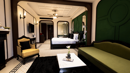 The Sohra Family Suite at Polo Resort Cherrapunji featuring a plush bed, elegant seating area, tiled flooring, and a ceiling fan.